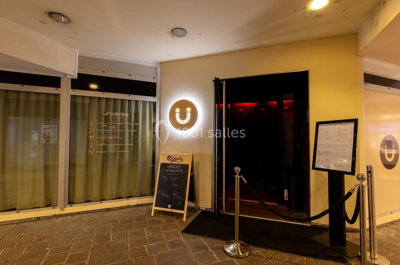 Entrée d'un établissement avec enseigne lumineuse en forme de U, menu affiché et tableau noir à l'extérieur.
