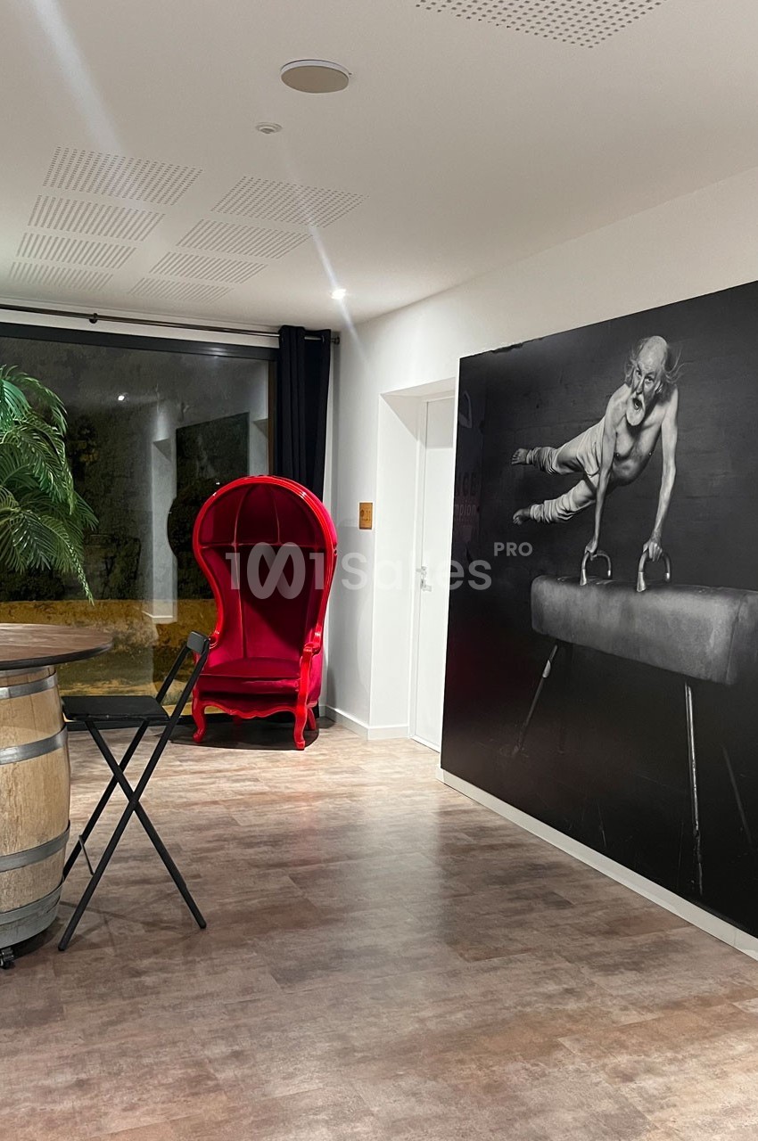 Salle moderne avec un fauteuil rouge, un tonneau en bois, une table pliante et une grande photo en noir et blanc au mur.