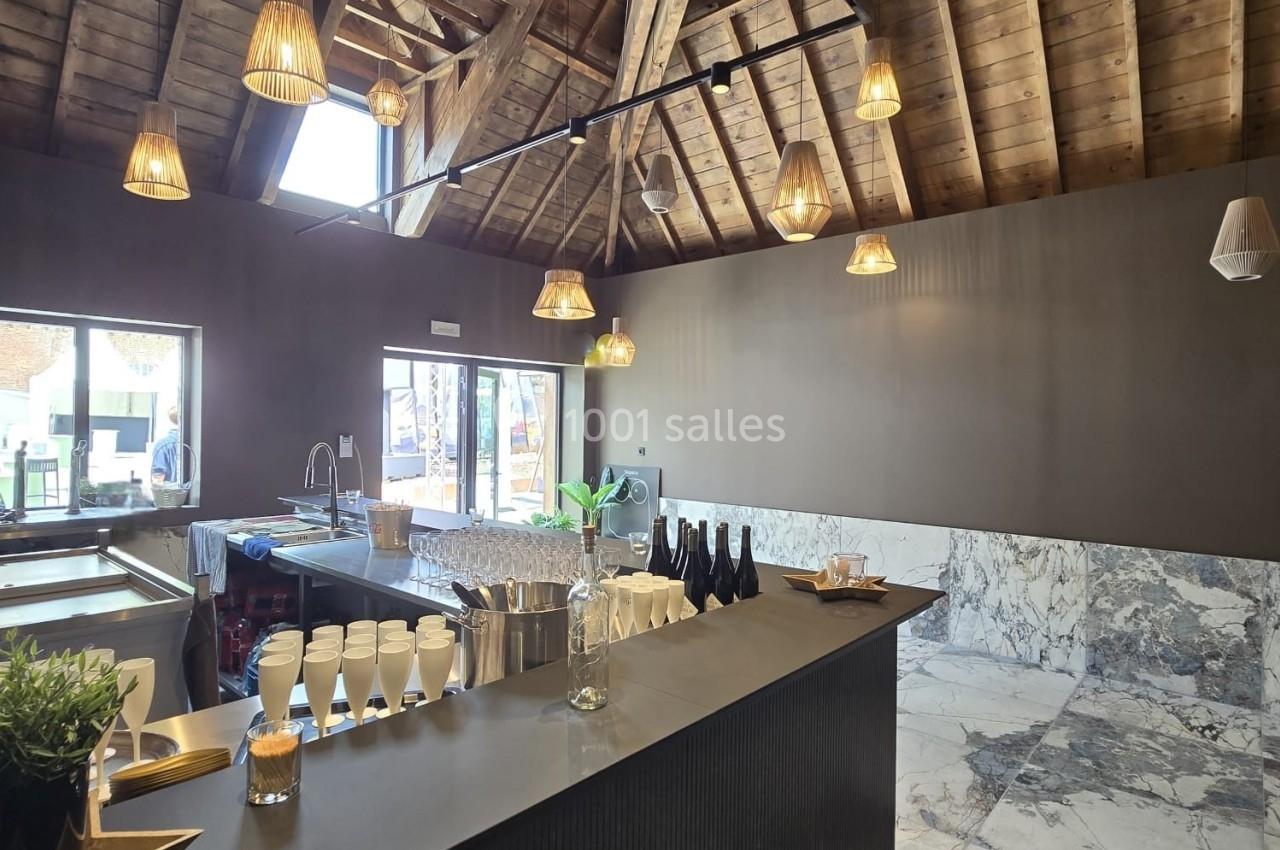 Intérieur d'un espace moderne avec un comptoir sombre, un plafond en bois apparent et des luminaires suspendus.