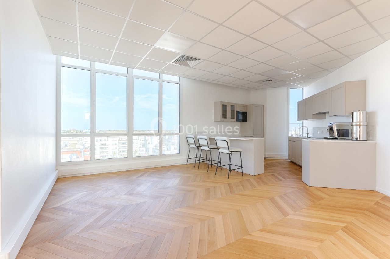Cuisine moderne ouverte avec îlot central, parquet en bois clair et grandes fenêtres laissant entrer la lumière naturelle.