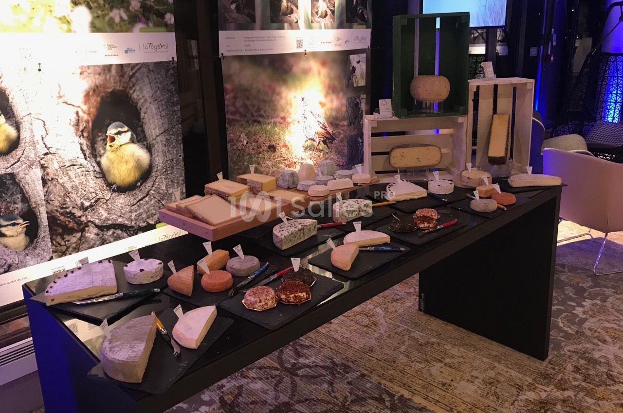 Table présentant une variété de fromages artisanaux sur des plateaux noirs, dans un cadre intérieur éclairé.