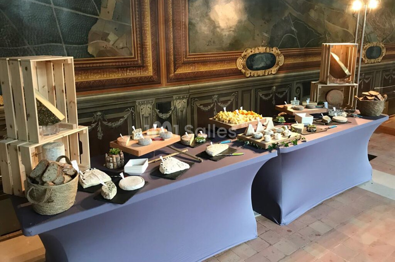 Table de buffet avec une sélection de fromages, pains et accompagnements, présentée dans un cadre élégant.