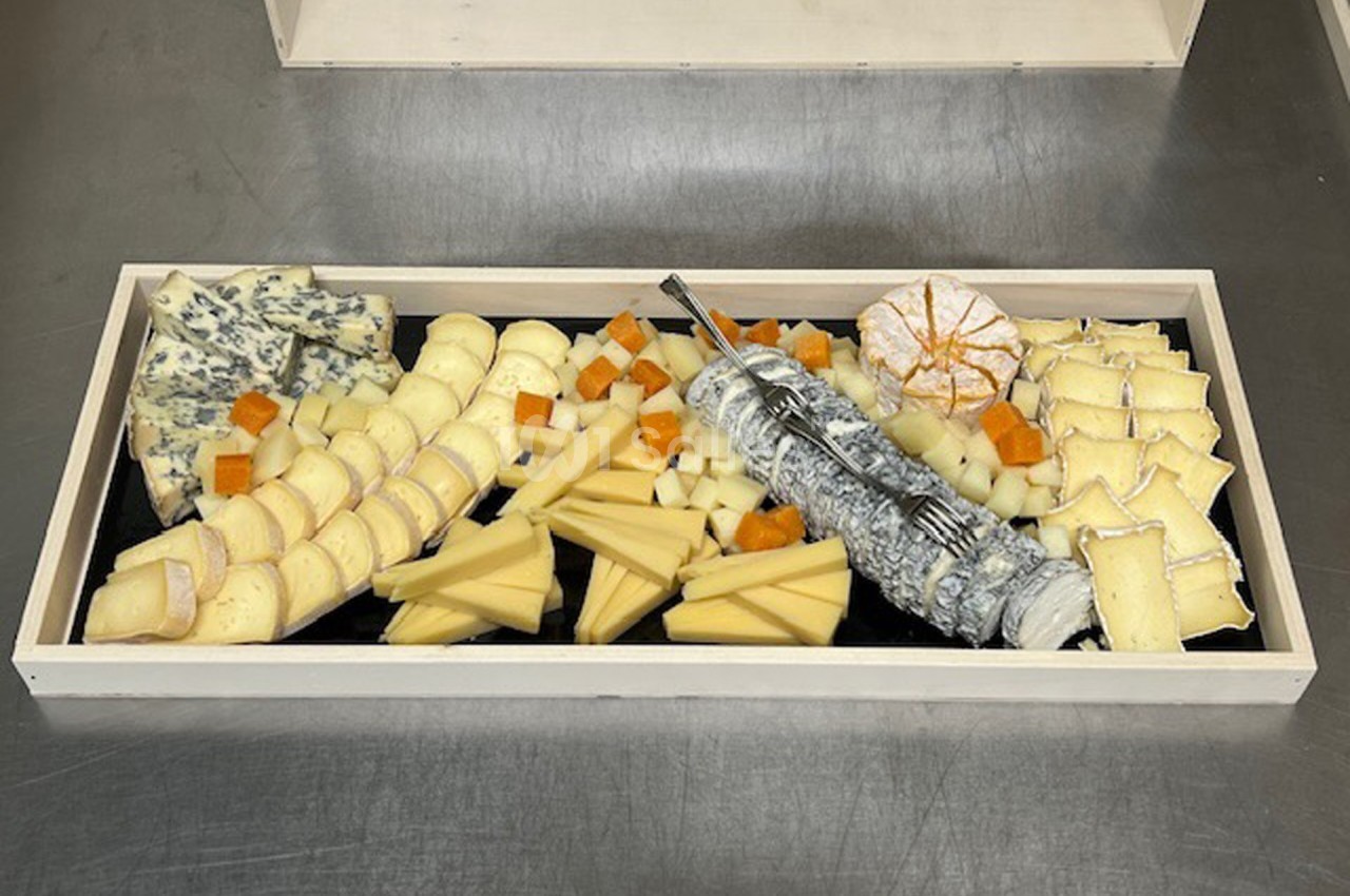 Plateau de fromages variés disposés sur un fond noir, incluant fromages à pâte dure, molle et persillée.