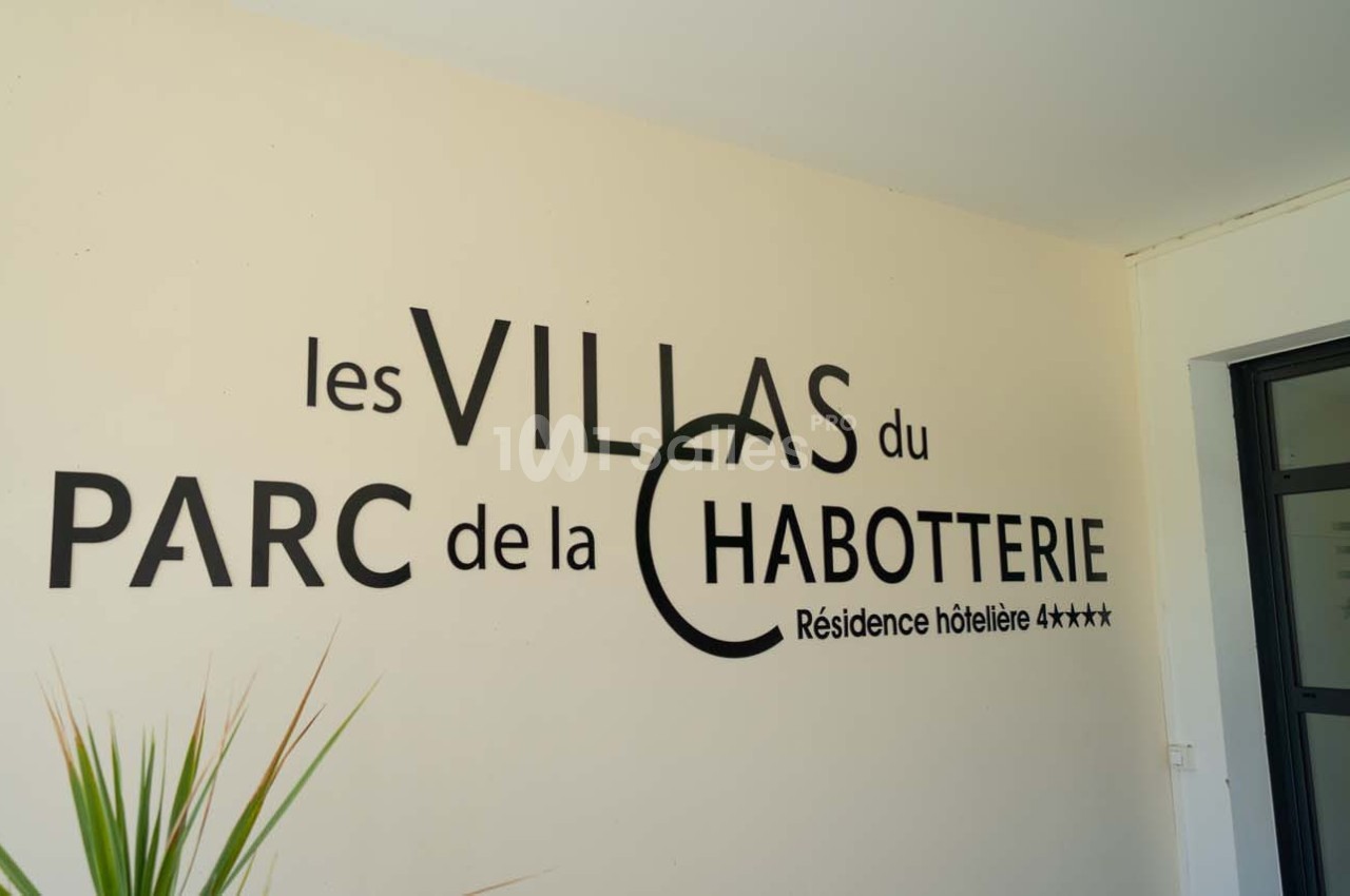 Texte ’Les Villas du Parc de la Chabotterie - Résidence hôtelière 4 étoiles’ sur un mur clair près d'une plante.