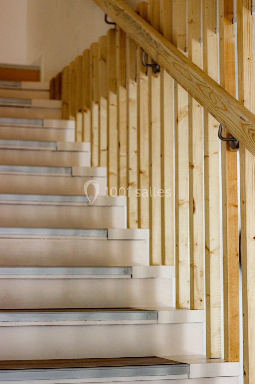 Escalier intérieur en bois clair avec une rampe assortie et des marches blanches dotées de bandes antidérapantes.