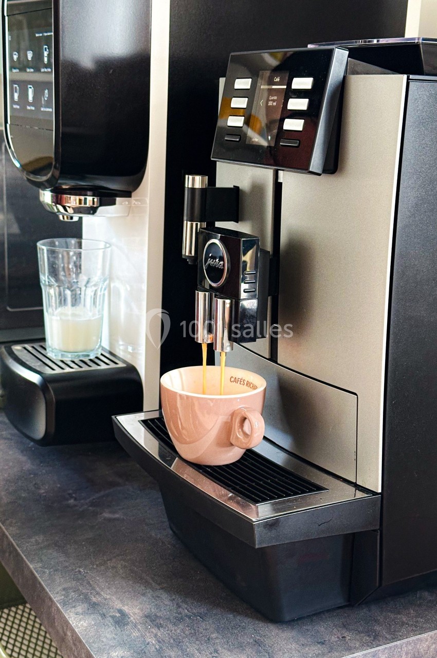 Machine à café automatique préparant un expresso dans une tasse beige posée sur son plateau.