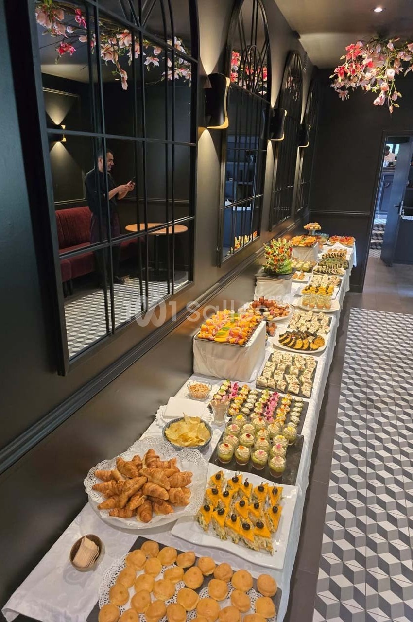 Buffet varié avec viennoiseries, desserts et fruits, disposé sur une longue table dans une salle élégante.