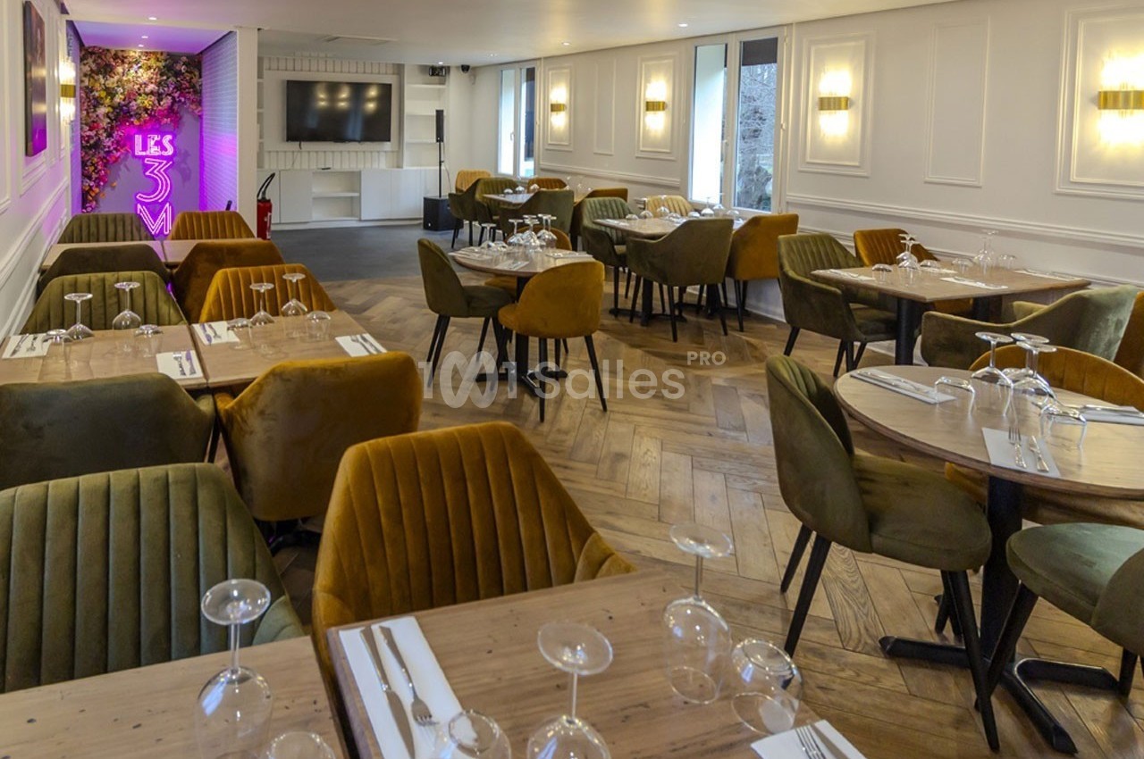 Salle de restaurant élégante avec tables dressées, chaises colorées et éclairage chaleureux.