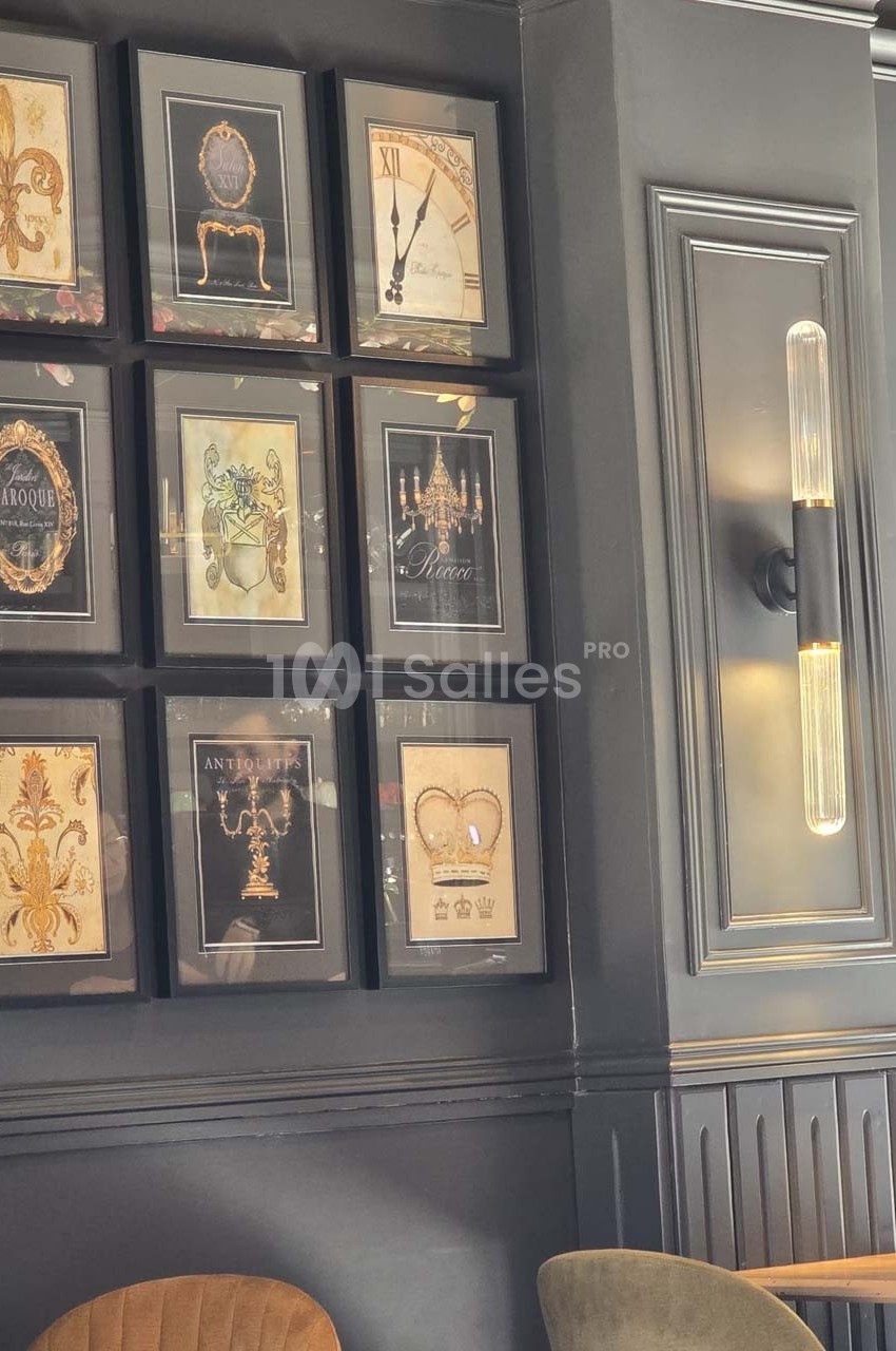 Mur décoré de cadres avec des illustrations variées et un éclairage mural moderne dans un intérieur élégant.
