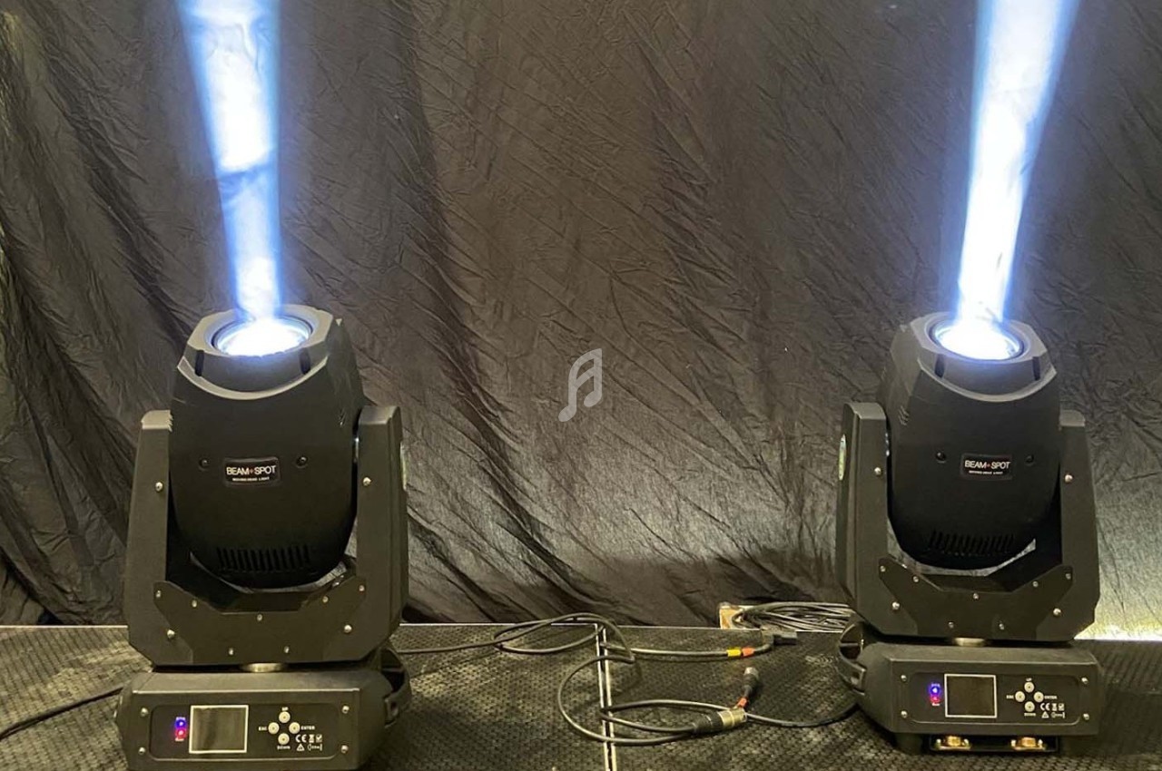 Deux projecteurs d'éclairage scénique émettant des faisceaux lumineux blancs sur un fond noir.