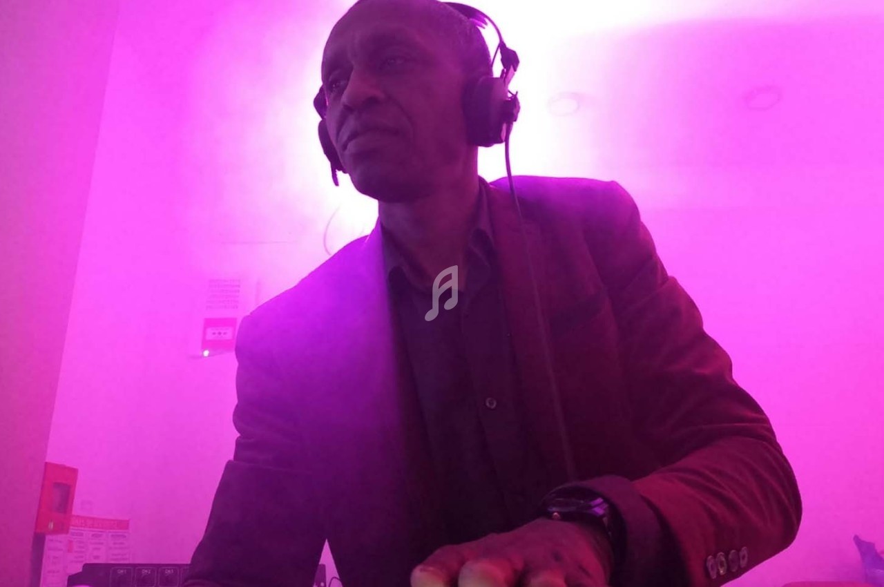 Homme portant un casque audio, concentré, dans une ambiance lumineuse rose.