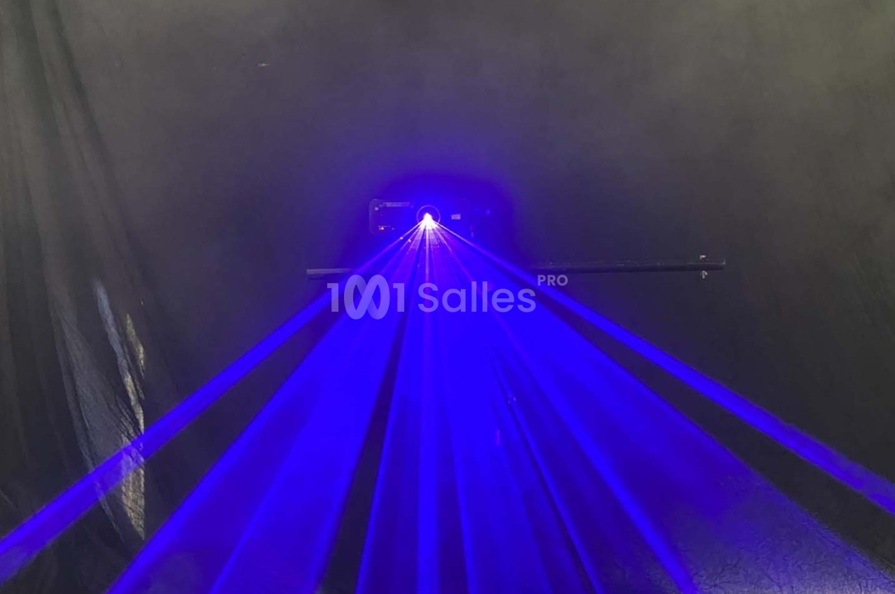 Rayons laser bleus émanant d'un appareil dans un environnement sombre avec un fond noir.