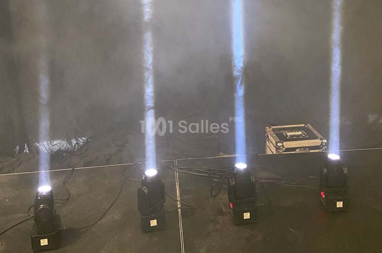 Quatre projecteurs émettant des faisceaux lumineux verticaux dans une ambiance enfumée, avec une boîte au sol.