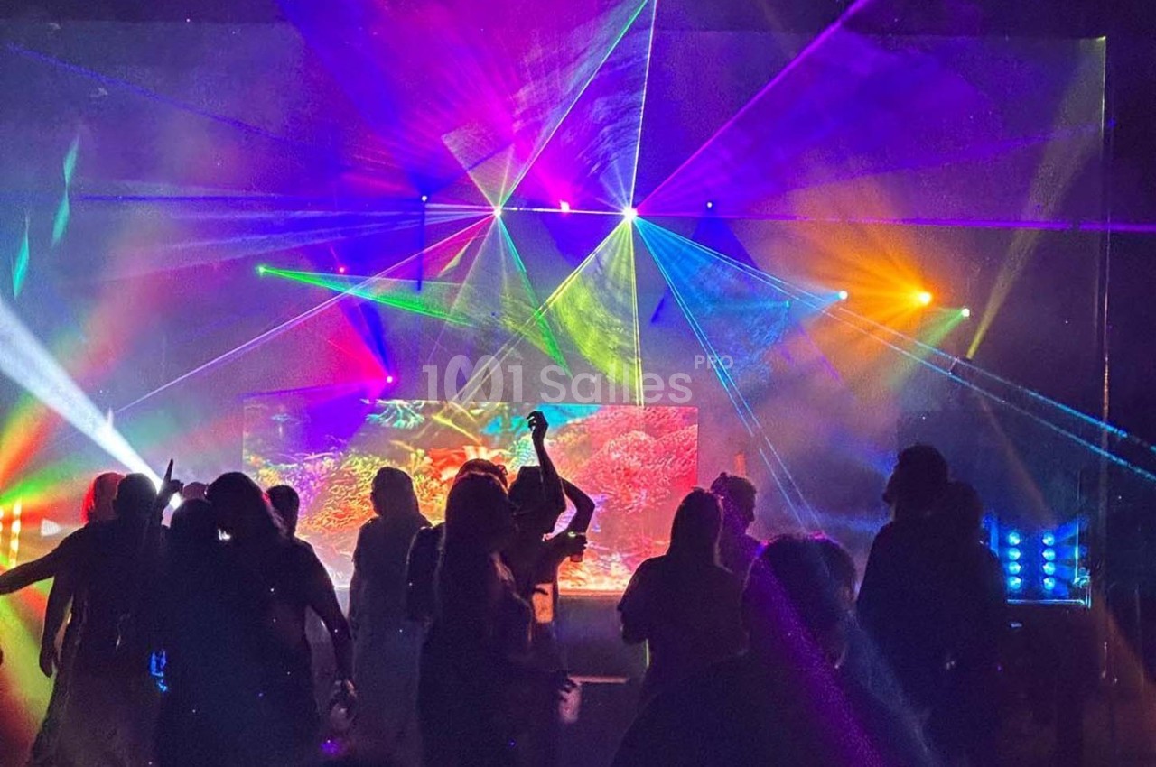 Personnes dansant dans une ambiance festive avec des jeux de lumières colorés et des lasers.