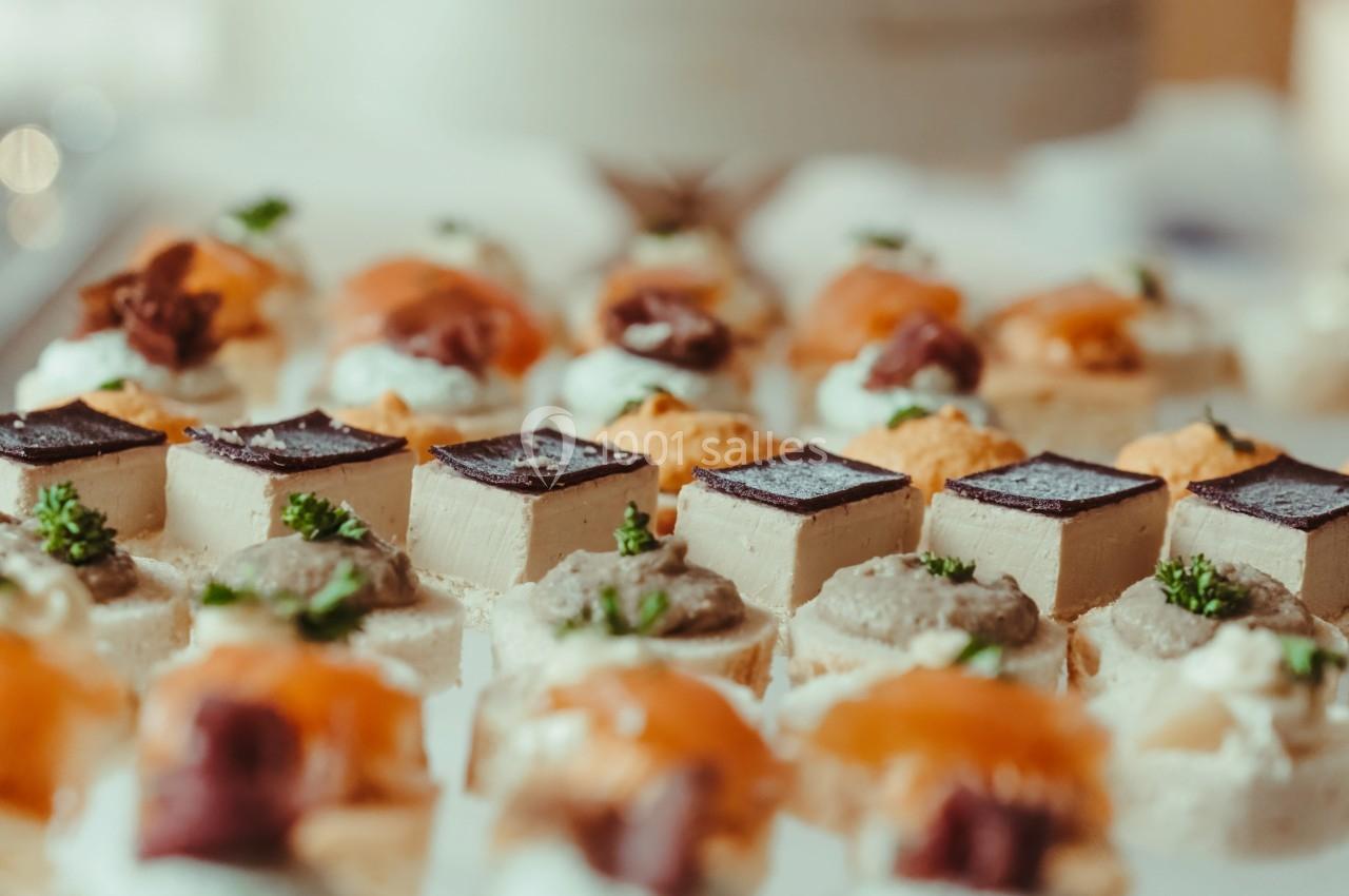 Plateau de canapés variés avec garnitures comme saumon, pâté et chocolat, disposés sur une table.