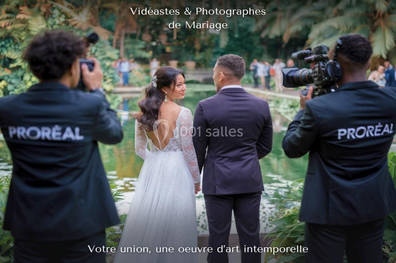 Un couple de mariés pose près d'un étang, entouré de vidéastes en pleine prise de vue.