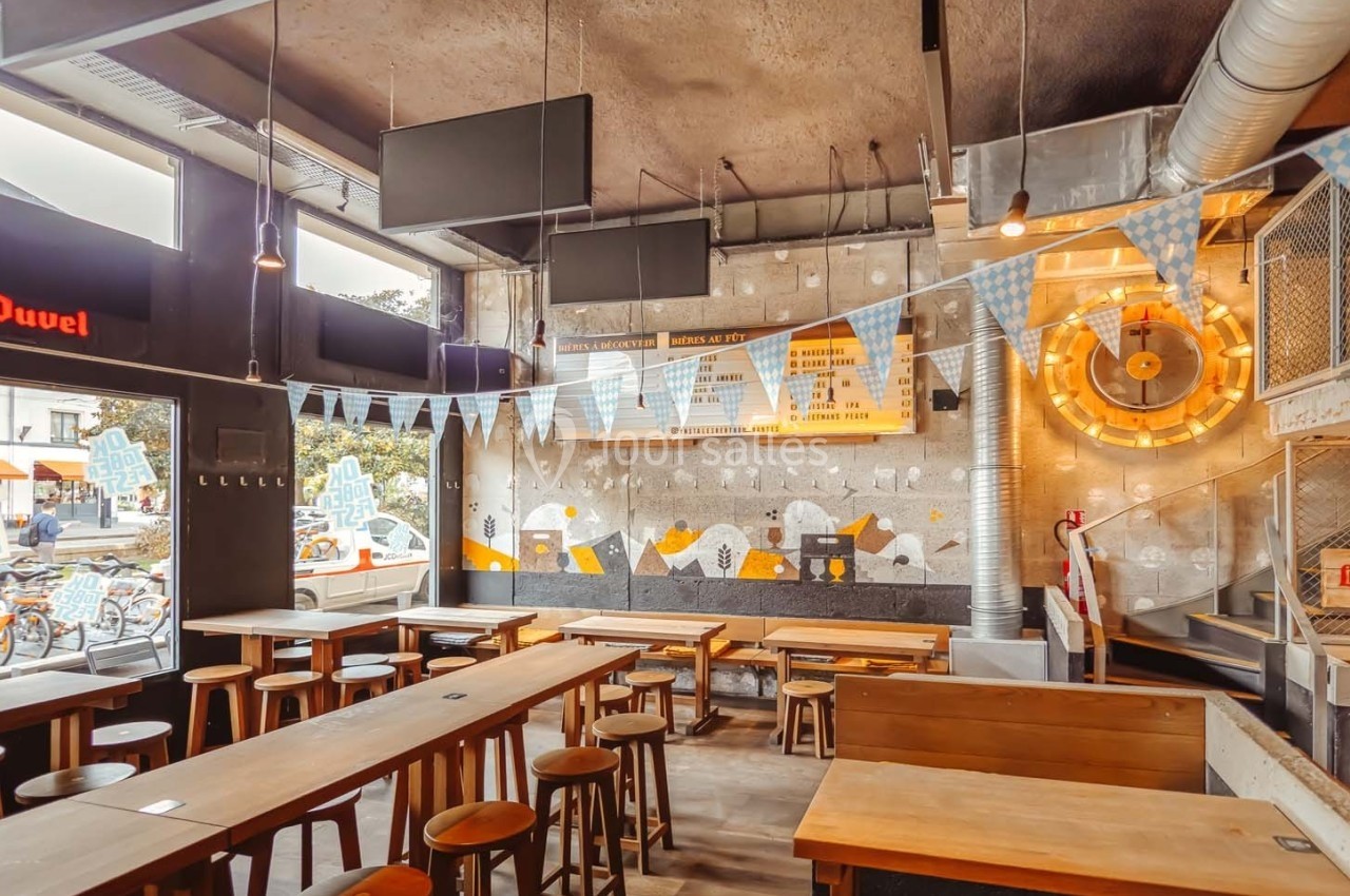 Intérieur d'un bar moderne avec tables en bois, guirlandes décoratives et un mur orné de motifs lumineux.