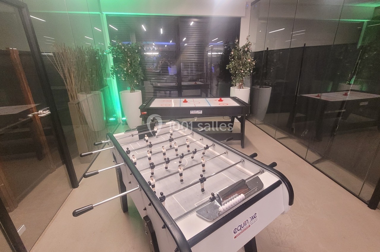 Salle de détente avec un baby-foot au premier plan et une table de hockey sur air en arrière-plan.