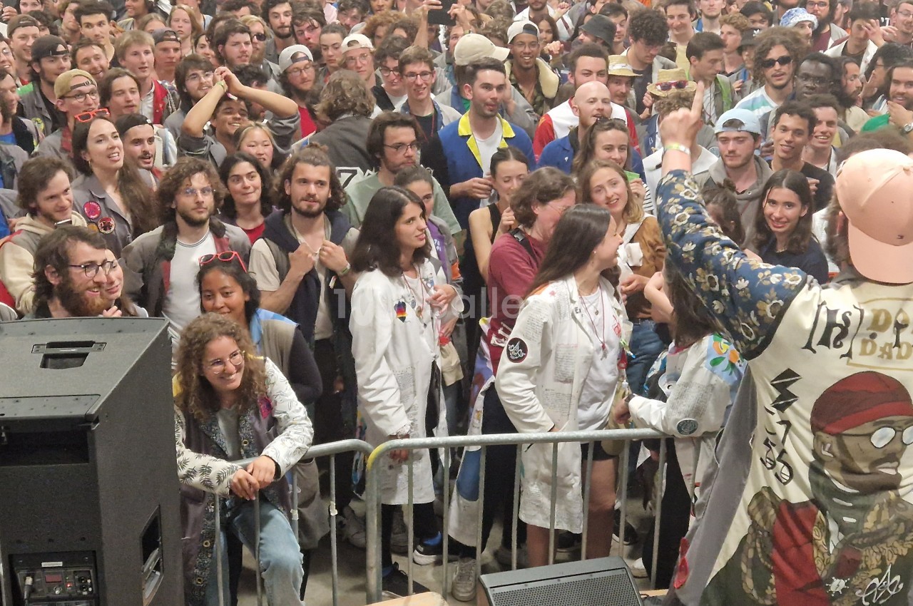 Un artiste s'adresse à une foule dense et enthousiaste lors d'un événement en plein air.