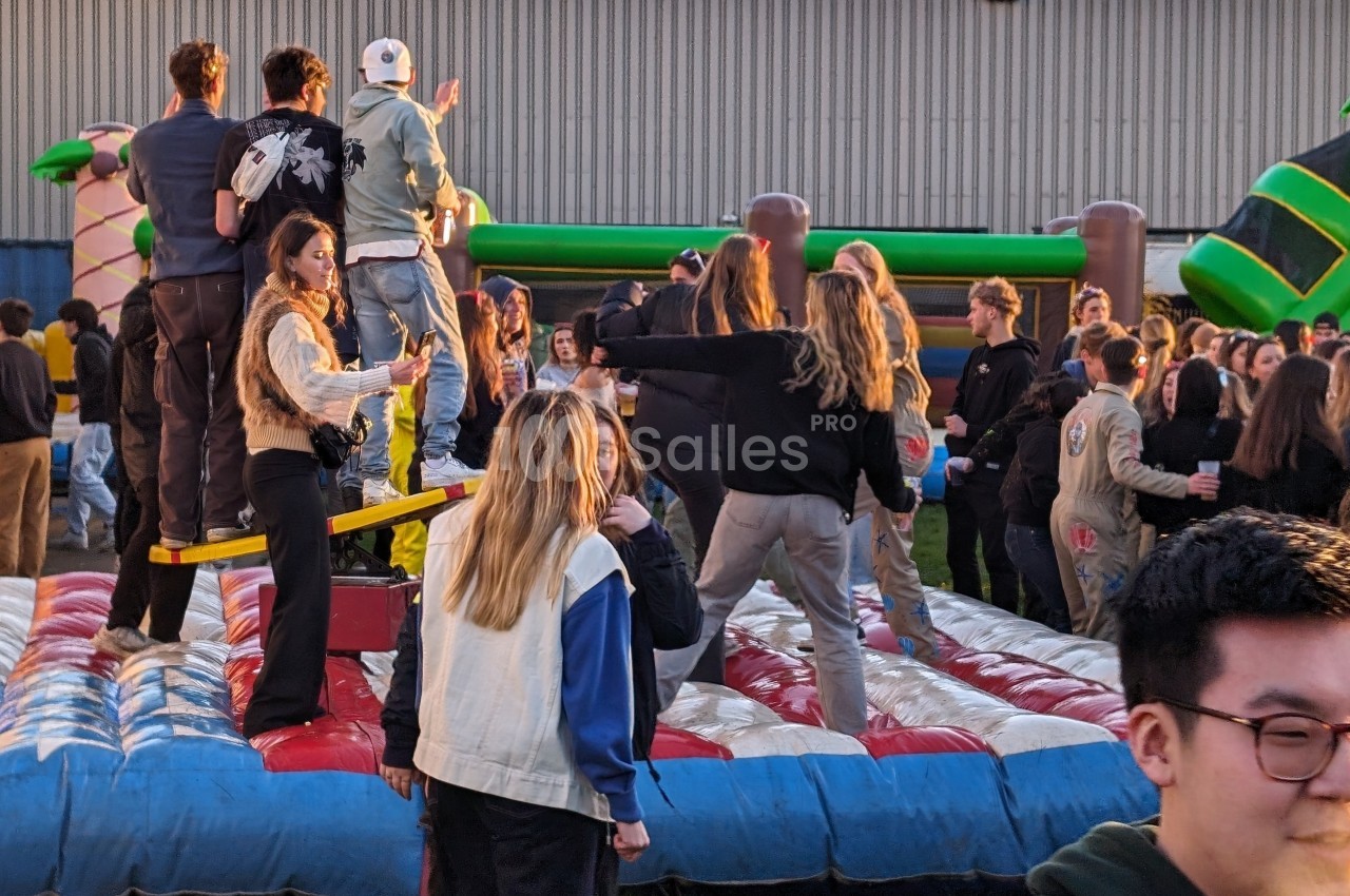 Des personnes participent à une activité sur une structure gonflable lors d'un événement en plein air.