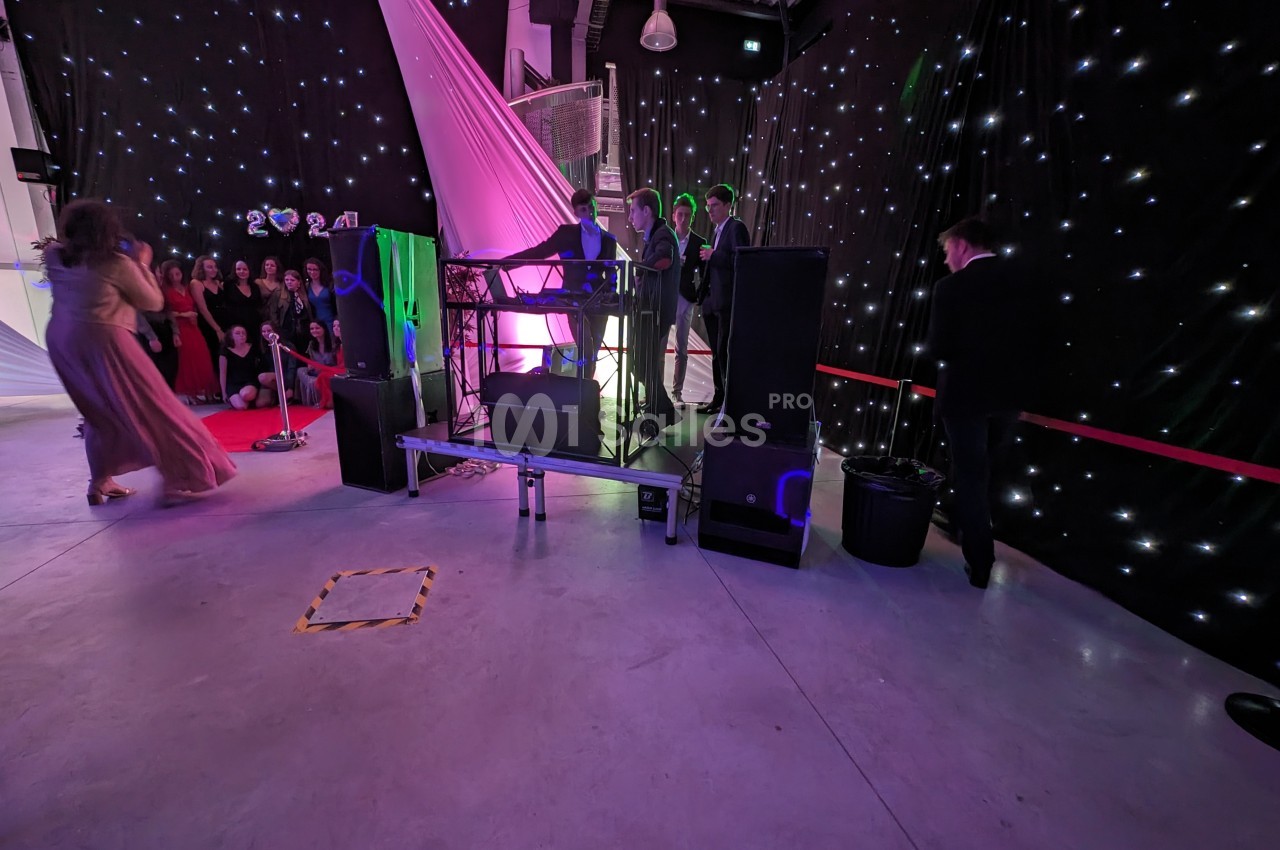 Un DJ anime une soirée dans une salle décorée de lumières étoilées, avec des invités en tenue de soirée.