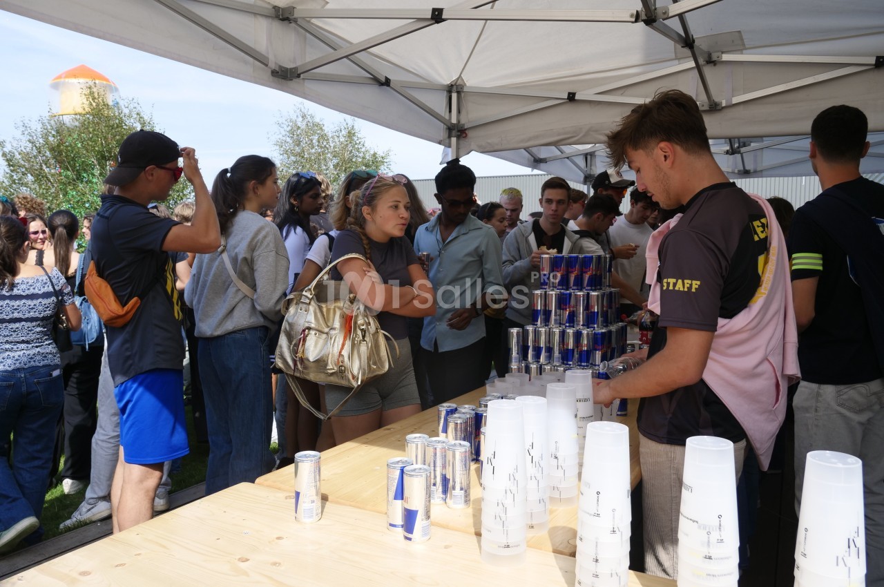 Des personnes font la queue sous des tentes pour recevoir des boissons servies par des bénévoles lors d'un événement en…
