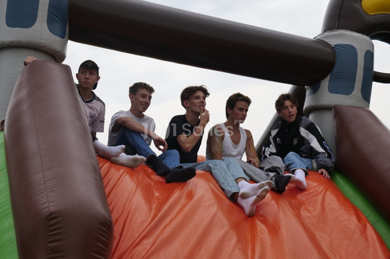 Six jeunes assis en haut d'une structure gonflable colorée, regardant dans différentes directions.