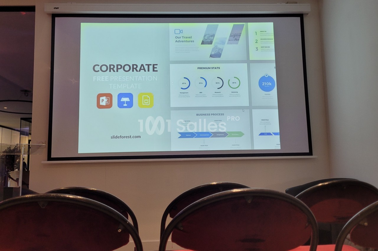 Écran de présentation affichant un modèle de diaporama d'entreprise dans une salle avec des chaises vides au premier plan.