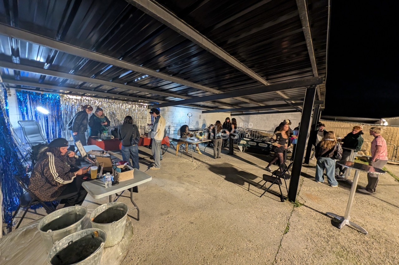 Des personnes rassemblées sous un abri en soirée, discutant et participant à des activités sur des tables installées.