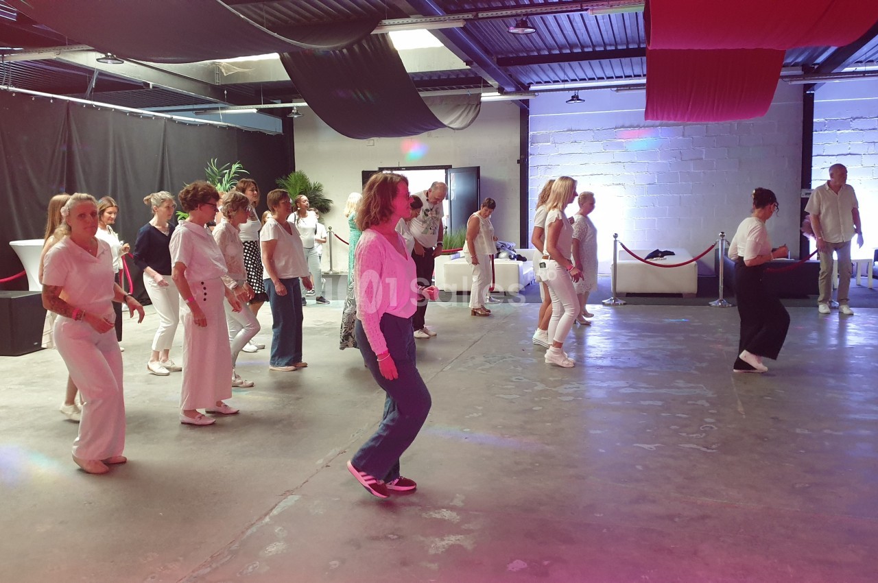 Groupe de personnes dansant en ligne dans une salle avec un éclairage coloré et un décor moderne.