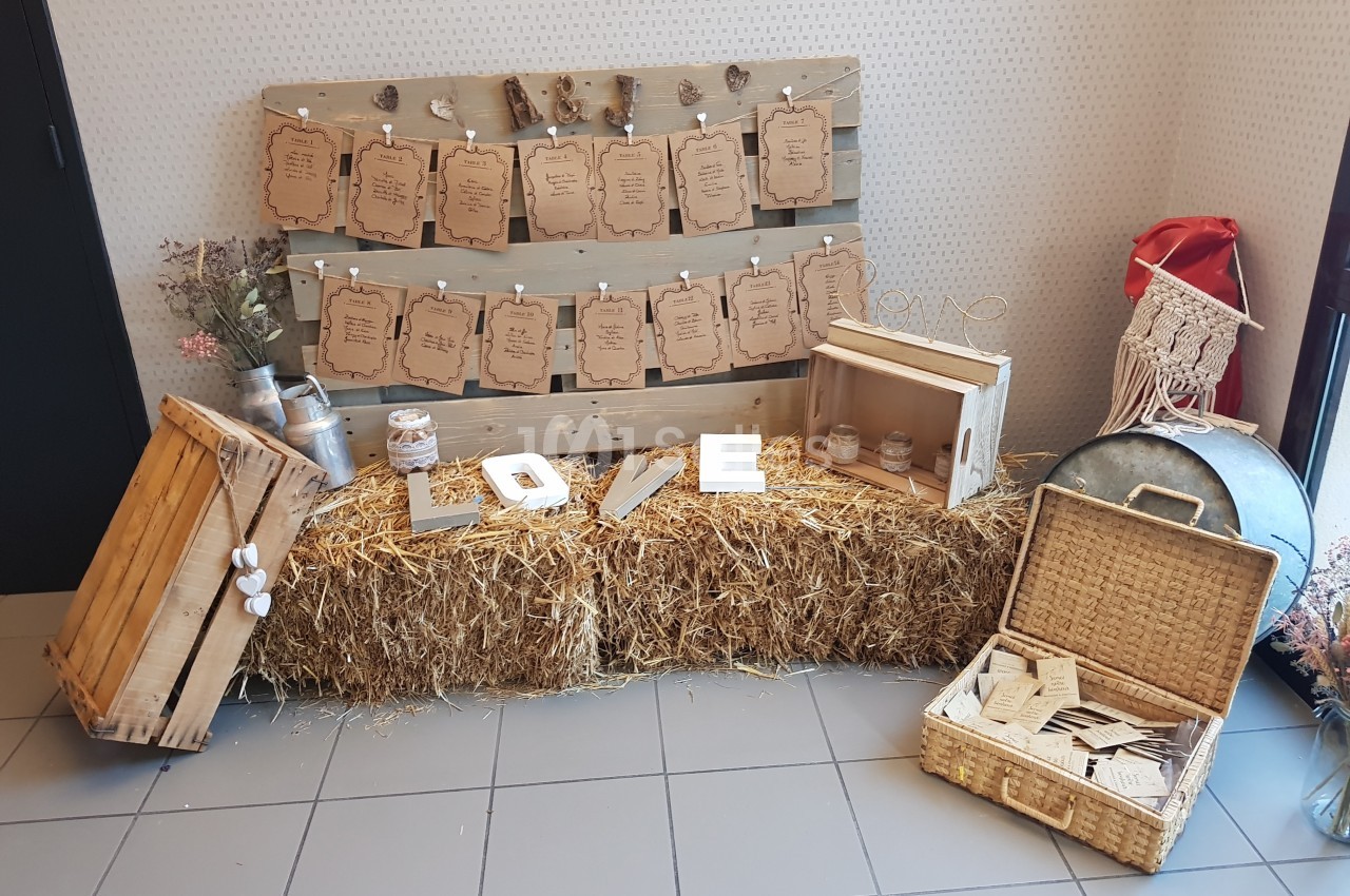 Décoration rustique avec ballots de paille, panneaux en bois, lettres ’LOVE’ et paniers pour une ambiance champêtre.