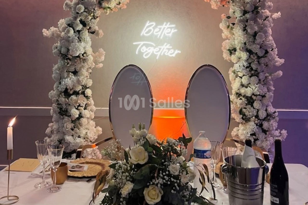 Table décorée pour un événement avec fleurs blanches, chandeliers, miroirs ovales et enseigne lumineuse ’Better Together’.
