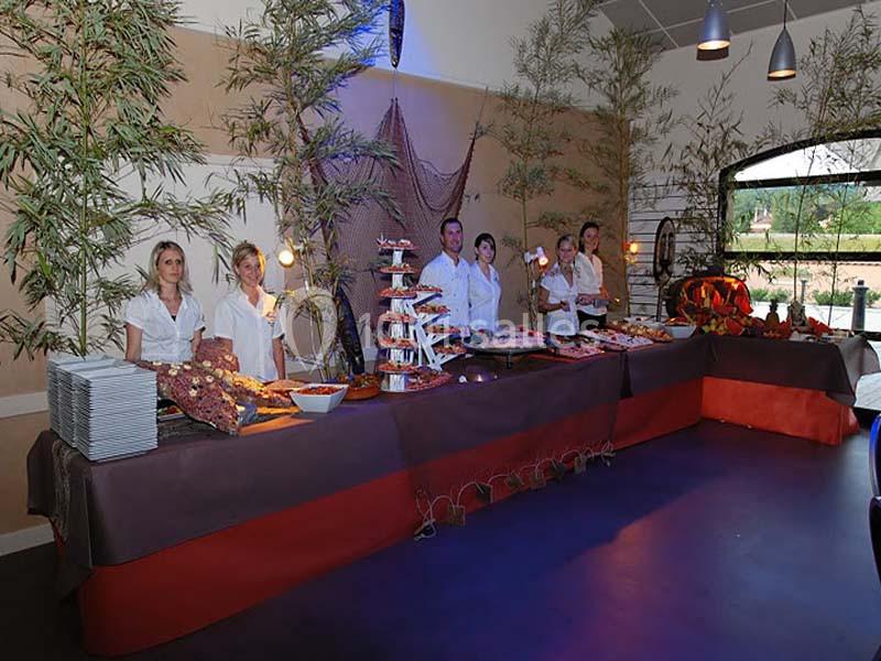 Buffet décoré avec des plats variés, servi par plusieurs personnes en tenue blanche dans une salle ornée de bambous.