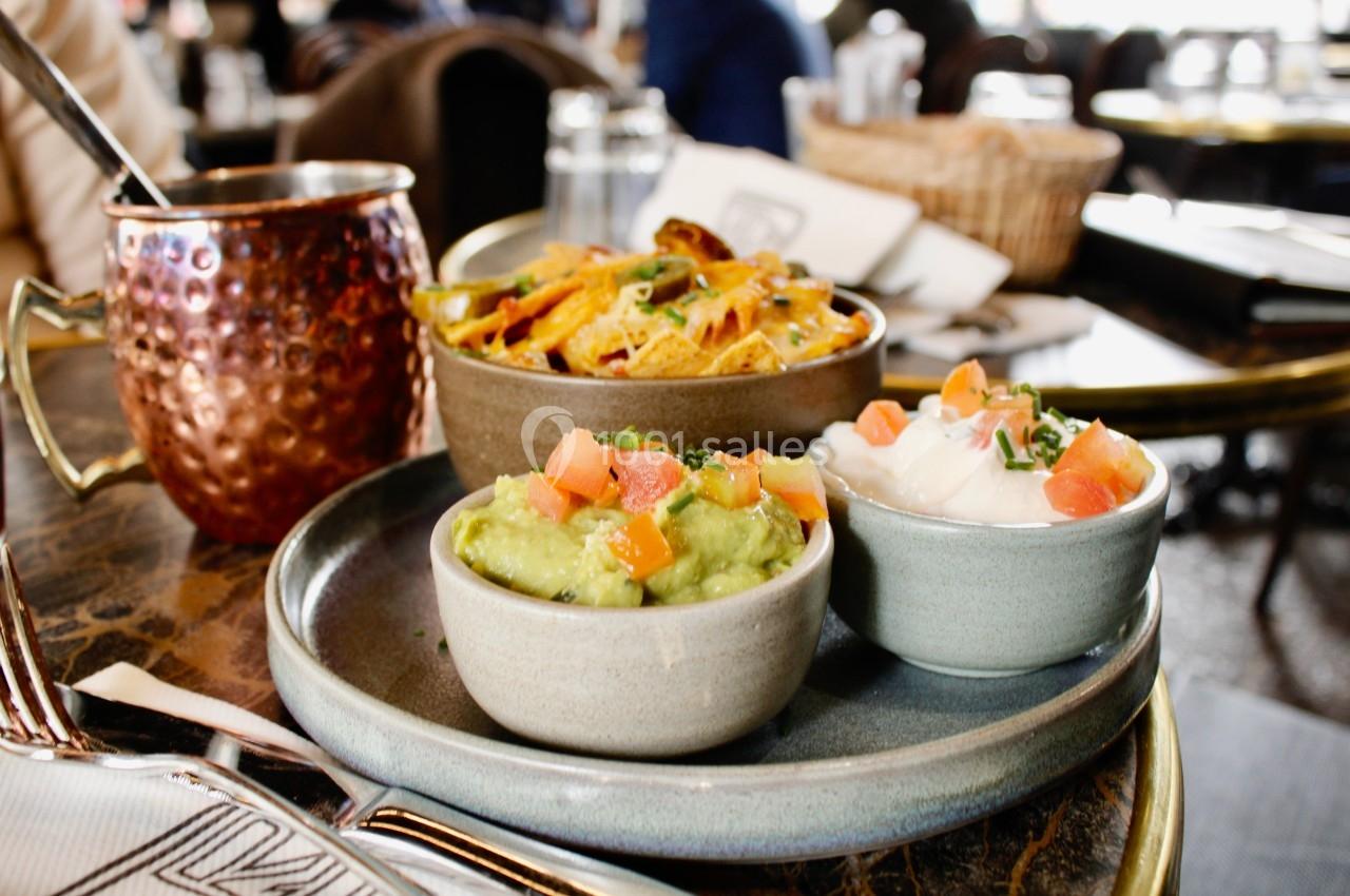 Assiette avec guacamole, crème fraîche, salsa et nachos sur une table dans un restaurant.
