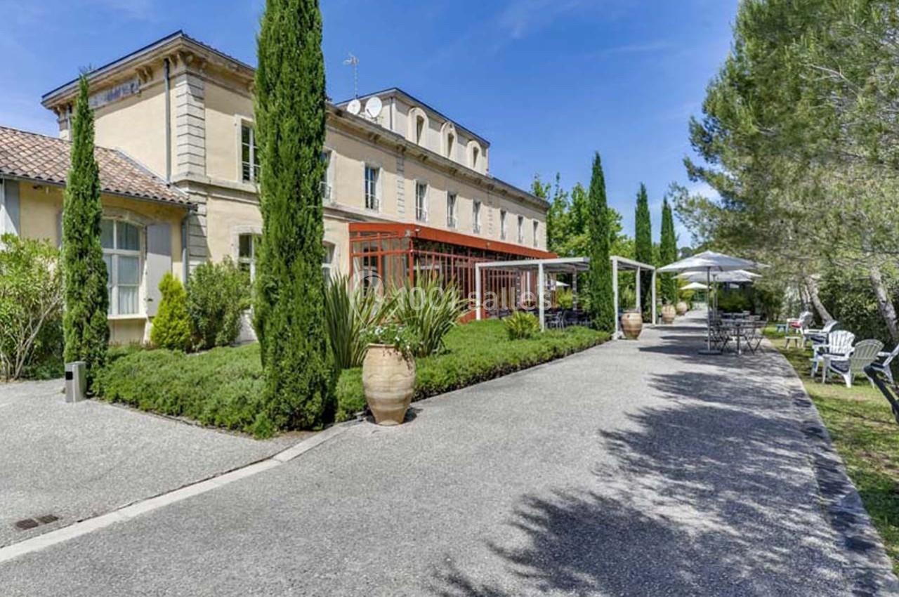 Bâtisse en pierre entourée de végétation méditerranéenne avec terrasse aménagée et allée gravillonnée.