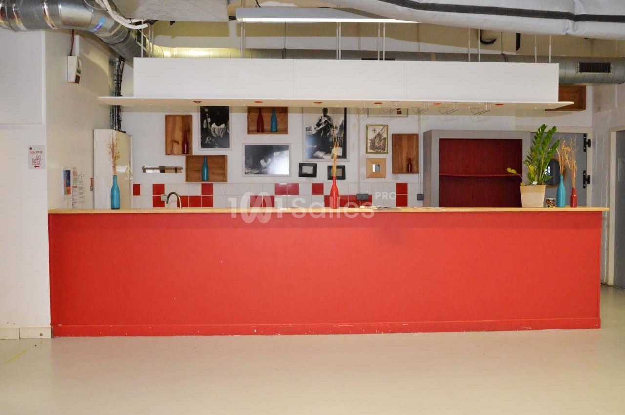 Comptoir rouge dans un espace intérieur moderne avec décorations murales, plantes et éclairage suspendu.