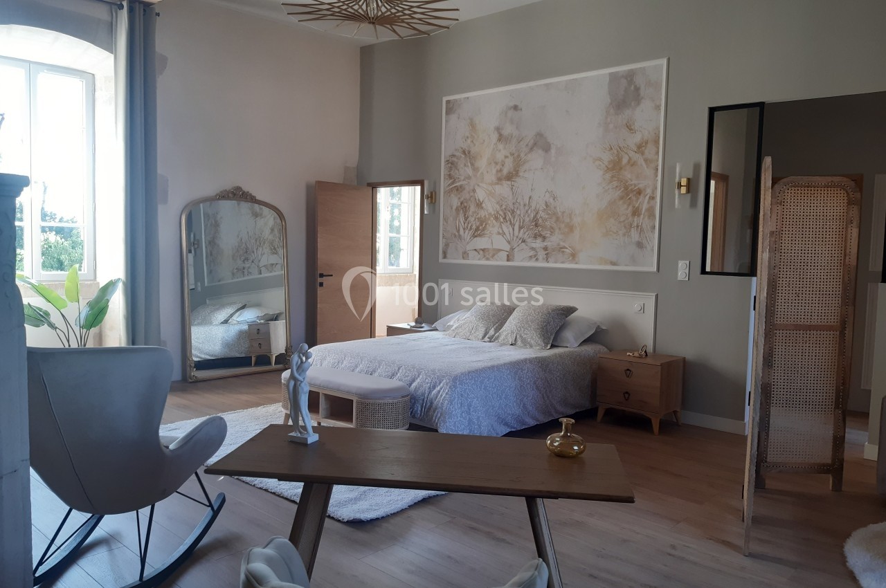 Chambre lumineuse avec lit double, bureau en bois, miroir sur pied et décoration murale dans un style épuré.