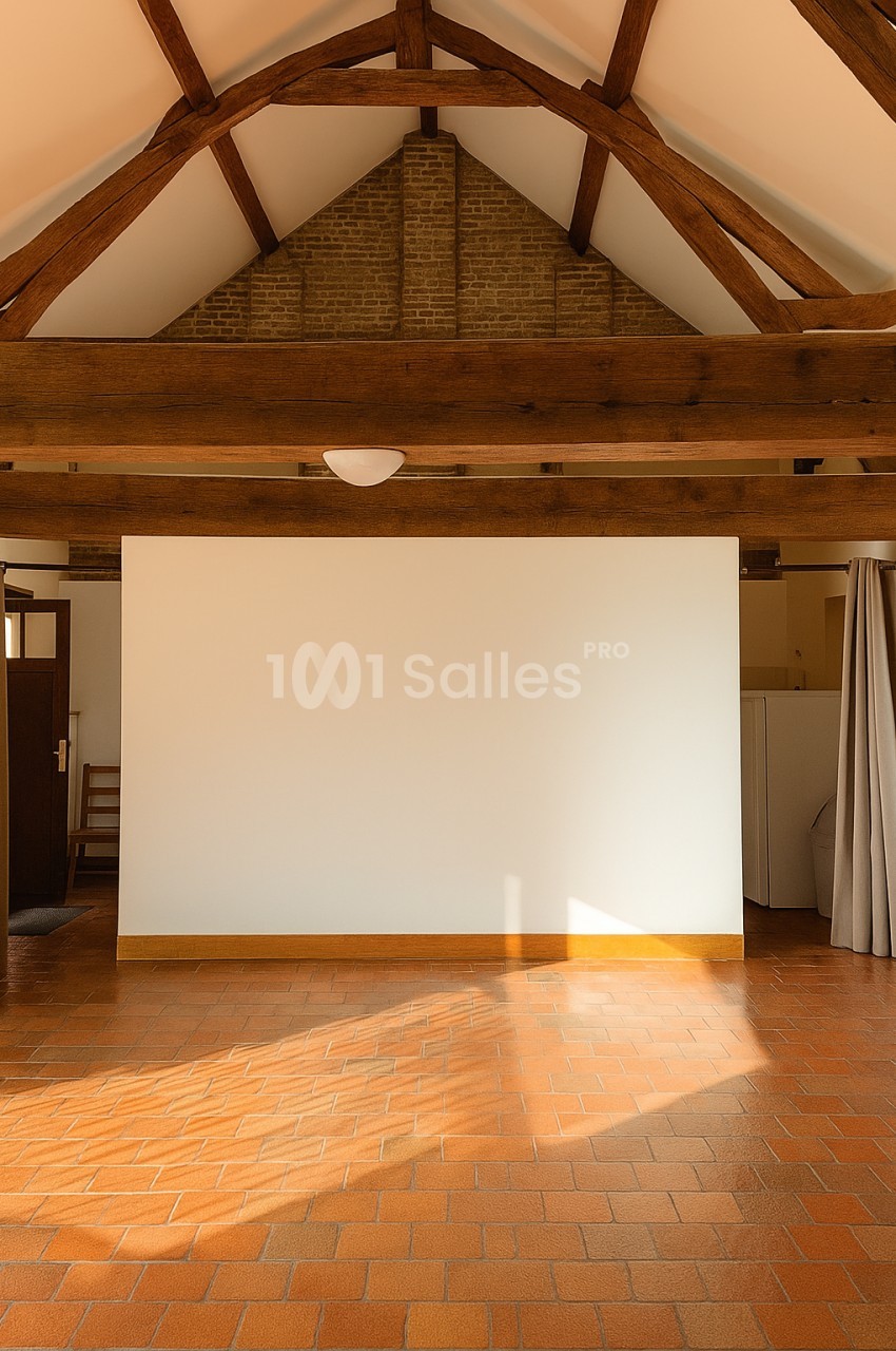 Plafond avec poutres apparentes en bois, mur blanc et sol en carrelage orange dans une pièce lumineuse.
