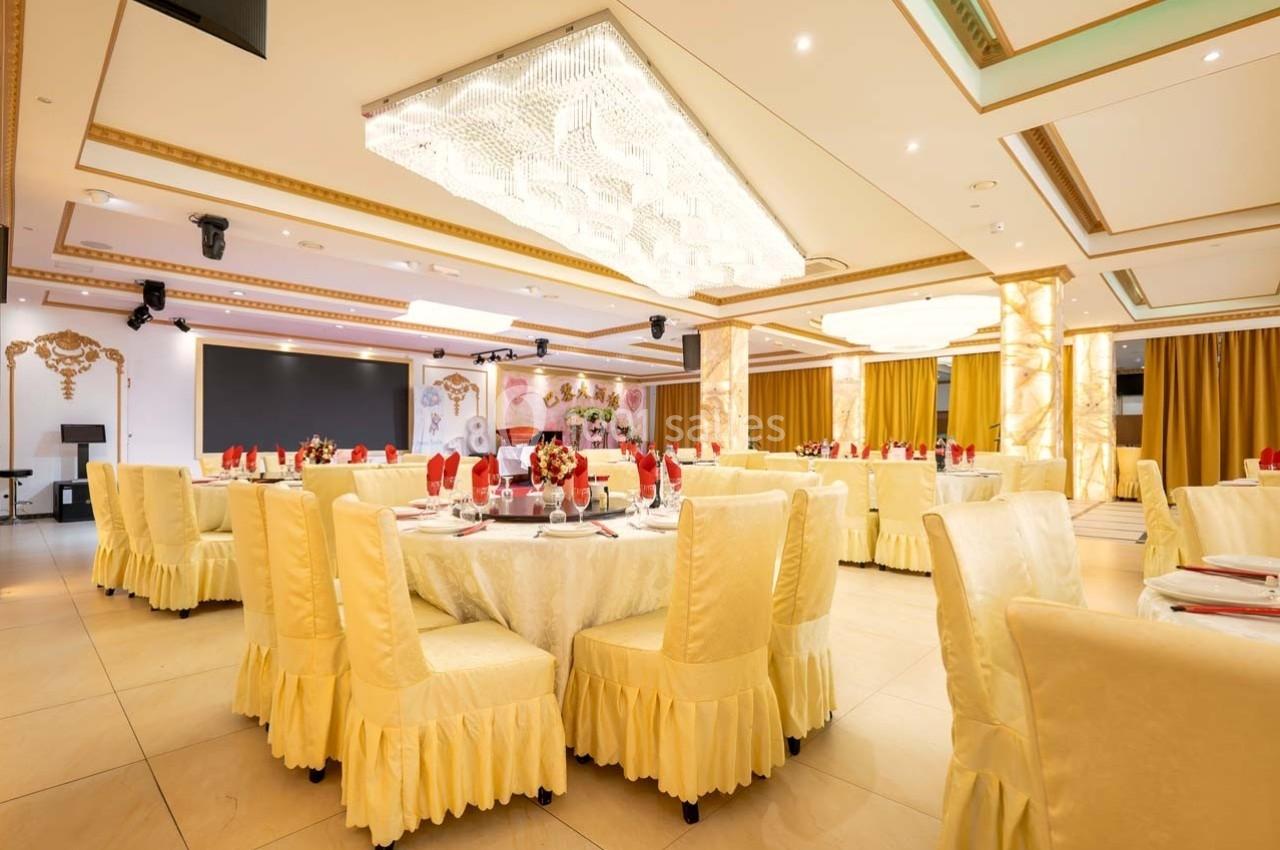 Salle de réception élégante avec tables rondes dressées, nappes et chaises jaunes, décorations raffinées et éclairage…
