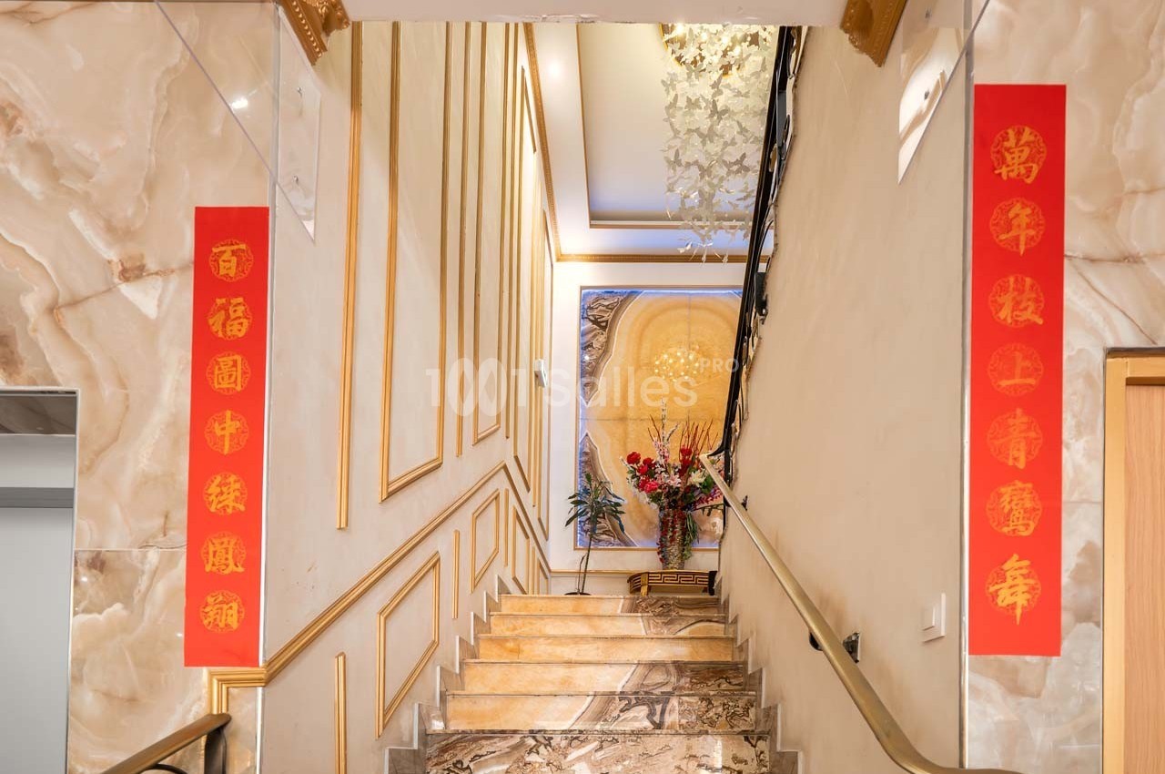 Escalier intérieur décoré de panneaux rouges avec des caractères chinois dorés et un grand tableau floral au mur.
