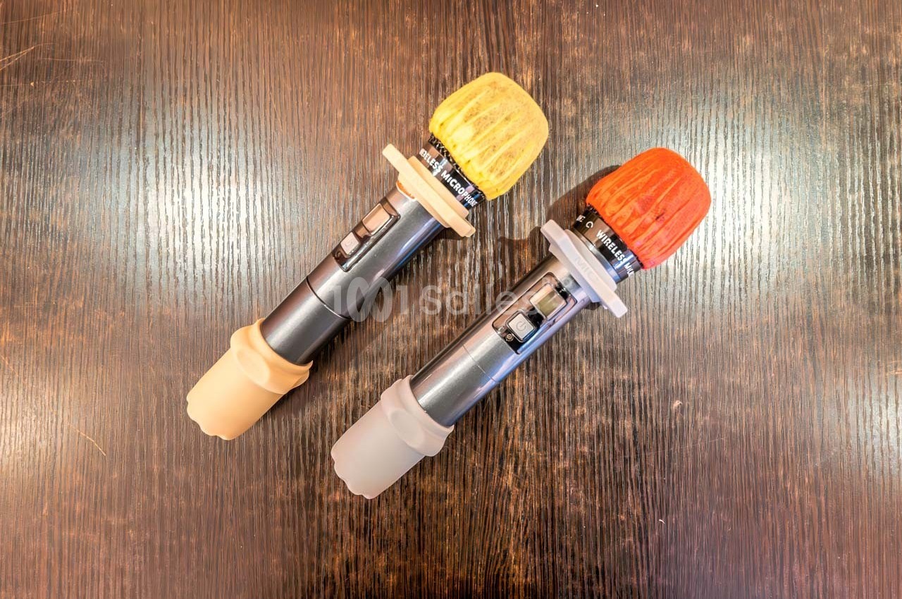 Deux poignées de sabres laser avec embouts colorés jaune et rouge, posées sur une surface en bois sombre.
