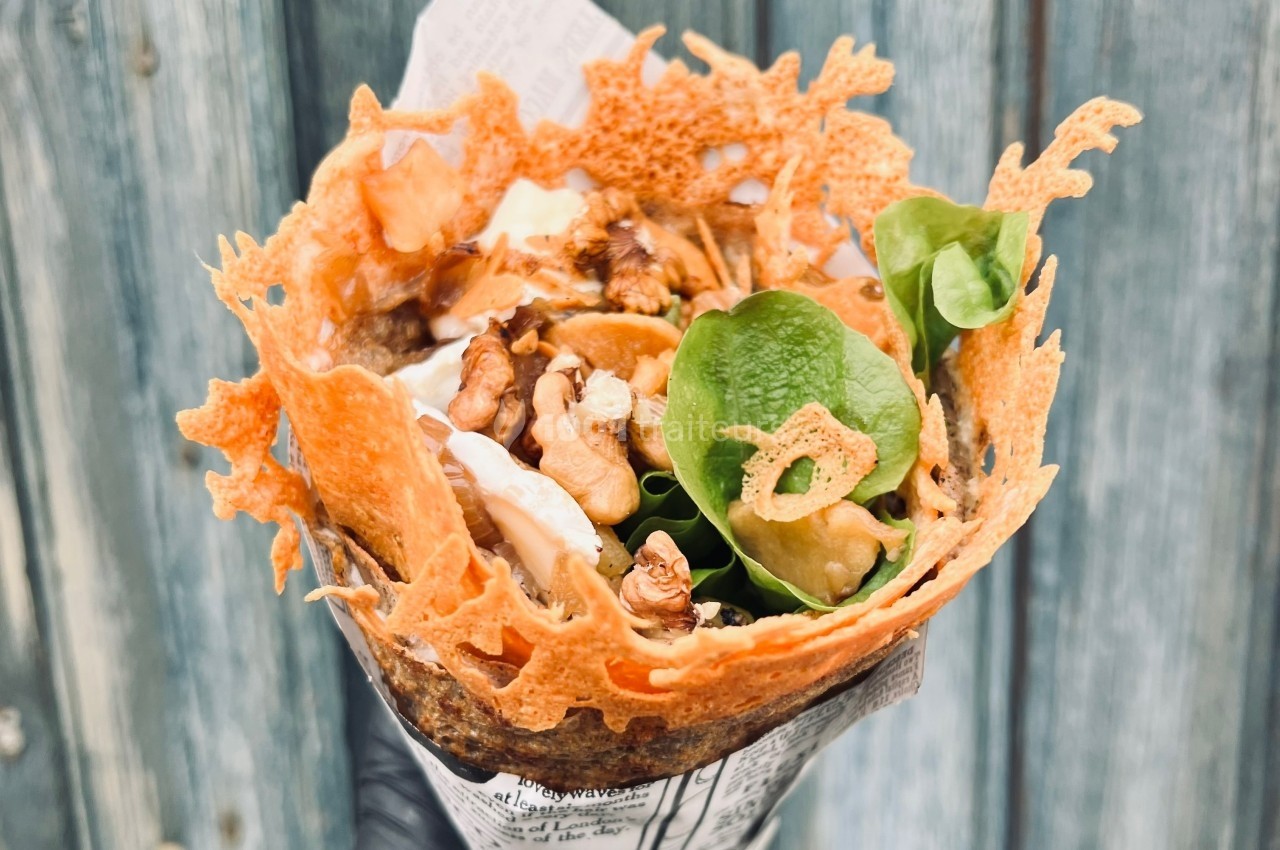 Crêpe garnie de noix, feuilles de salade et fromage, entourée d'une dentelle de fromage croustillante.