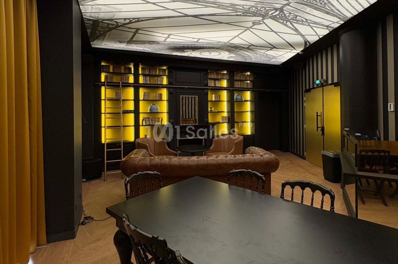 Salle élégante avec canapé en cuir, étagères éclairées, table noire et plafond décoratif rétro.