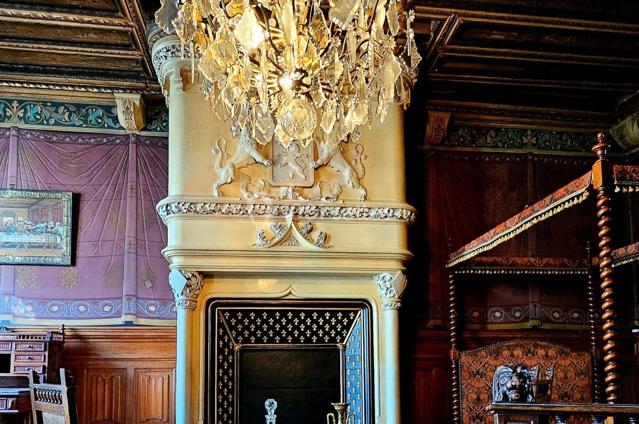 Intérieur d'une pièce ancienne avec cheminée ornée, lustre en cristal, meubles en bois et décorations raffinées.
