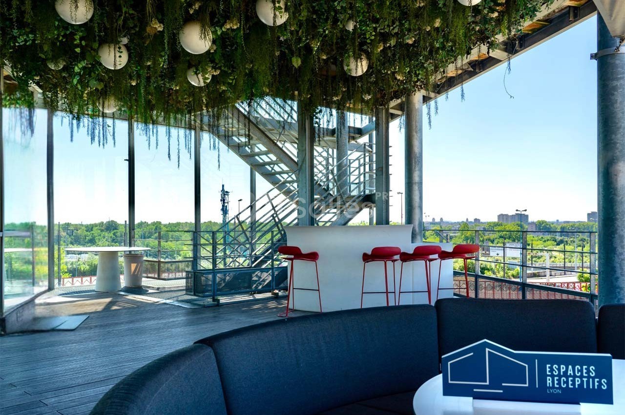Terrasse couverte avec vue dégagée, mobilier moderne, plafond végétalisé et escalier métallique en arrière-plan.