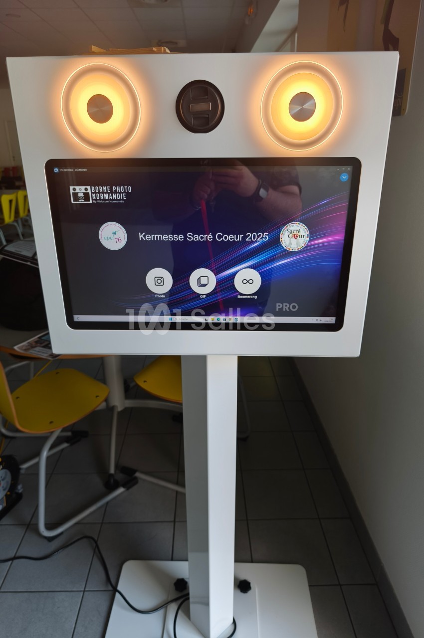 Borne photo interactive sur pied avec écran tactile affichant un menu pour un événement nommé ’Kermesse Sacré Coeur 2025’.