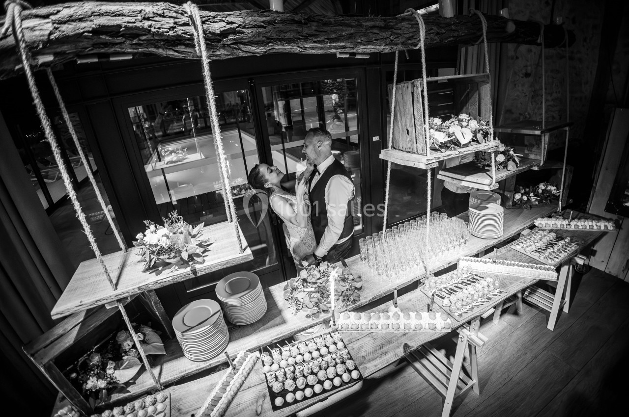 Un couple dansant près d'un buffet décoré de bois et de cordes, avec des plats et des verres disposés.
