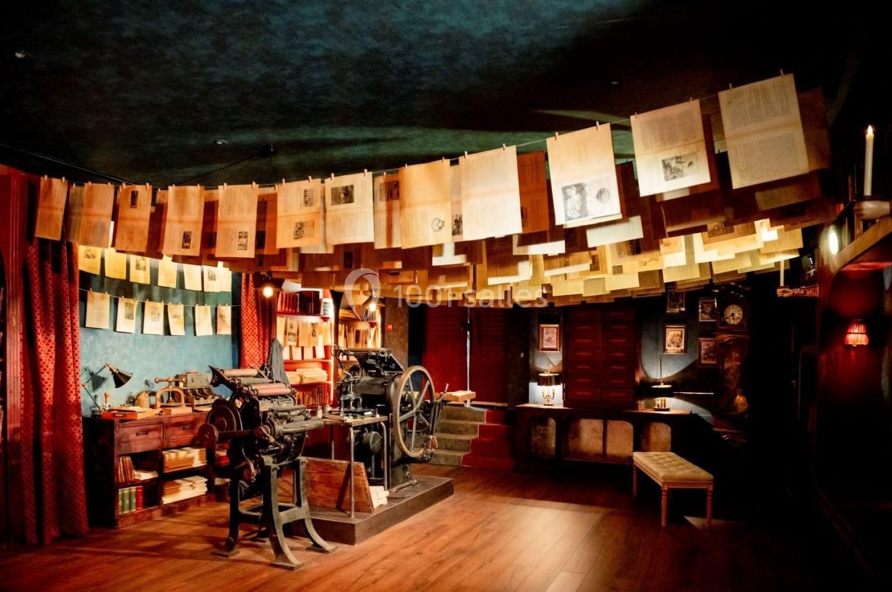 Atelier d'imprimerie ancienne avec une presse mécanique et des feuilles suspendues dans un décor rétro.