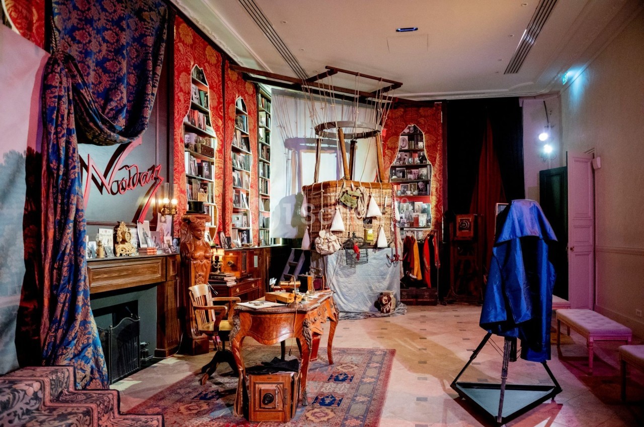Salle décorée avec des meubles anciens, des étagères remplies de livres et un ballon suspendu au centre.