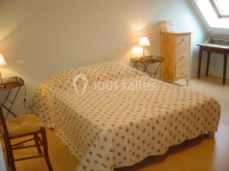 Chambre avec un lit double couvert d'une couette à motifs, deux lampes de chevet et un mobilier en bois clair.